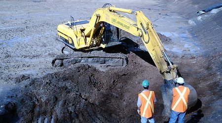Trabajadores junto a una excavadora en obra civil