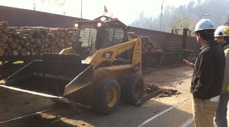 Minicargador y personal en planta industrial
