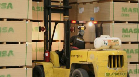 Grúa horquilla moviendo tableros en bodega